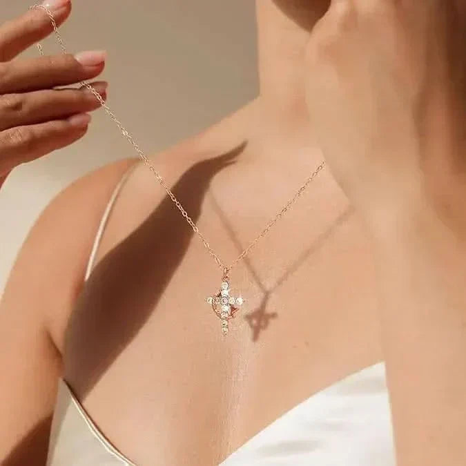 Close view of a model's collarbone as she lifts the sparkling cross pendant by its delicate chain 3