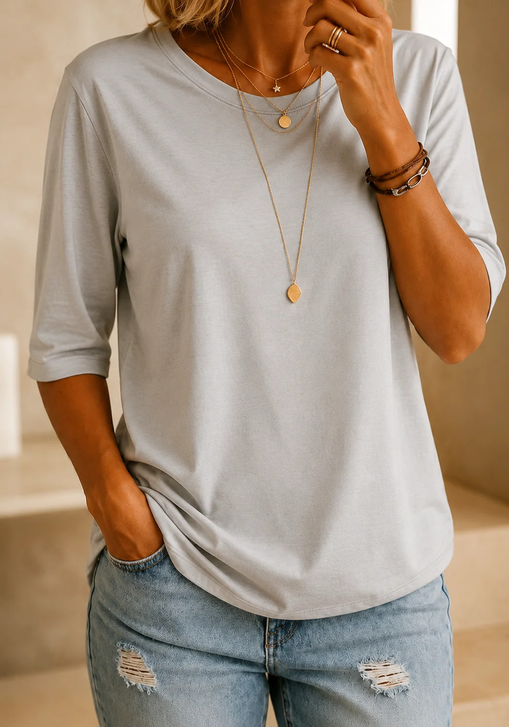 Light heather gray half-sleeve tee with a crewneck and layered gold necklaces, another view.