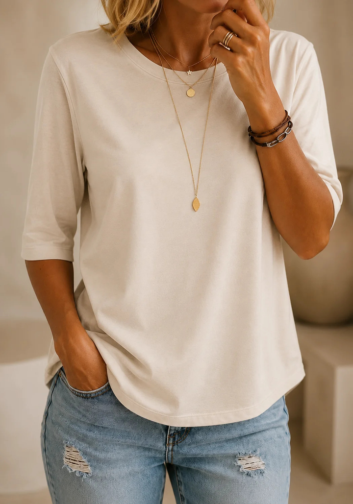 Cream half-sleeve tee with a crewneck and layered gold necklaces, another view.