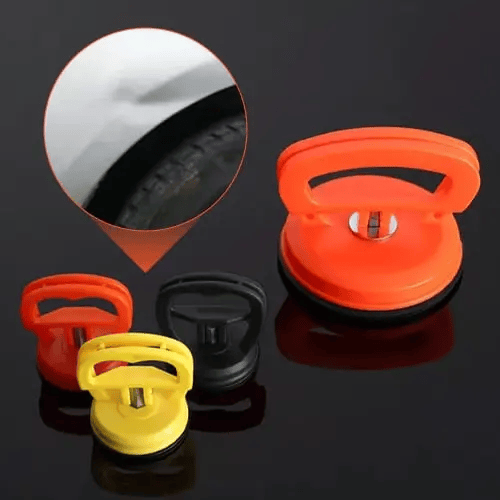 Orange, yellow and black suction pullers on a dark surface, with an inset detail showing a small dent above a car wheel arch.