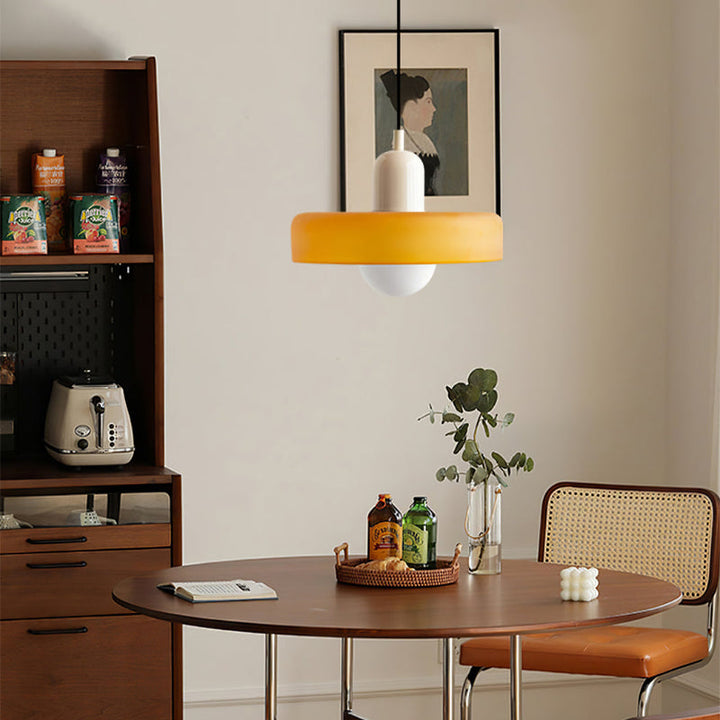 Amber pendant with cream cap hanging over a round wooden dining table near a shelf unit 30