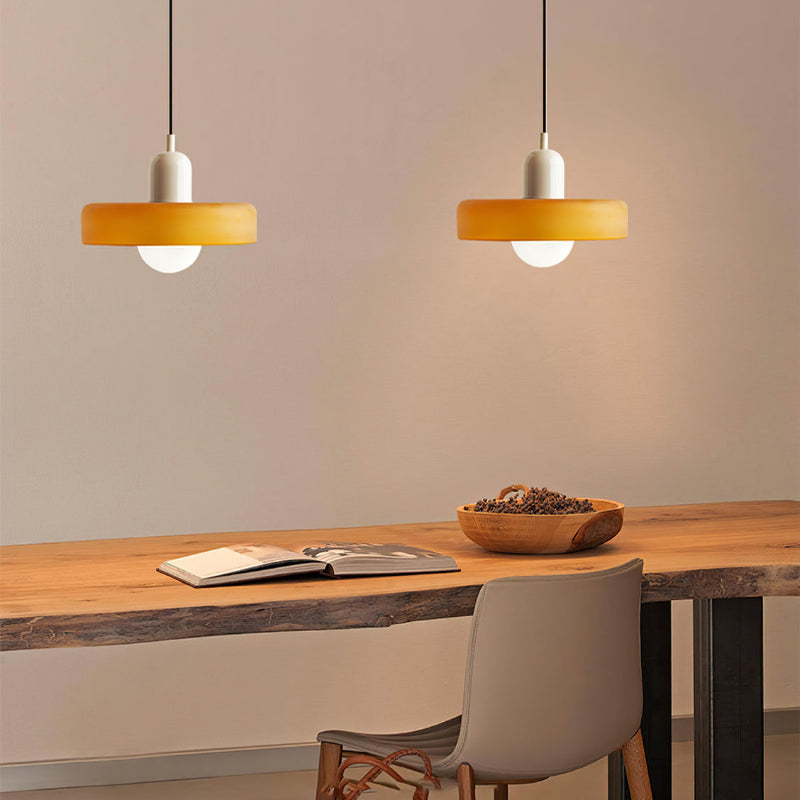 Two amber pendants with white caps glow above a live-edge wooden desk with an open book 33