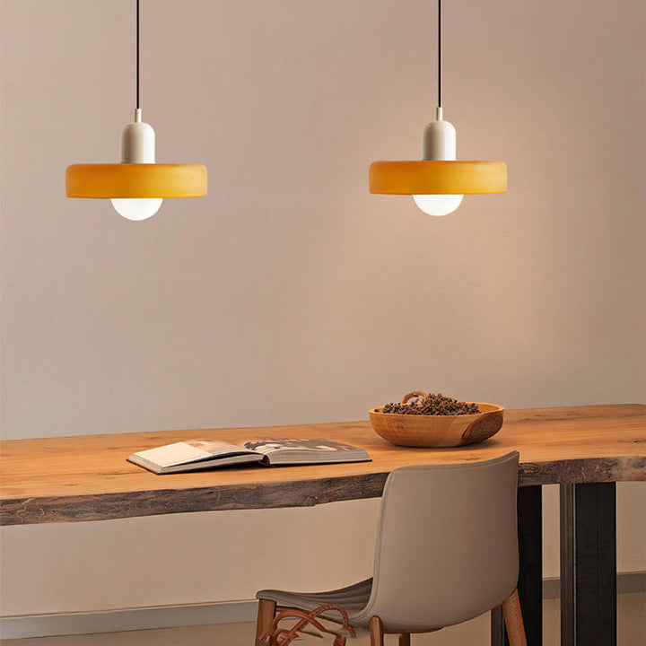 Two amber pendants with cream caps glowing above a live-edge wooden desk with an open book 32