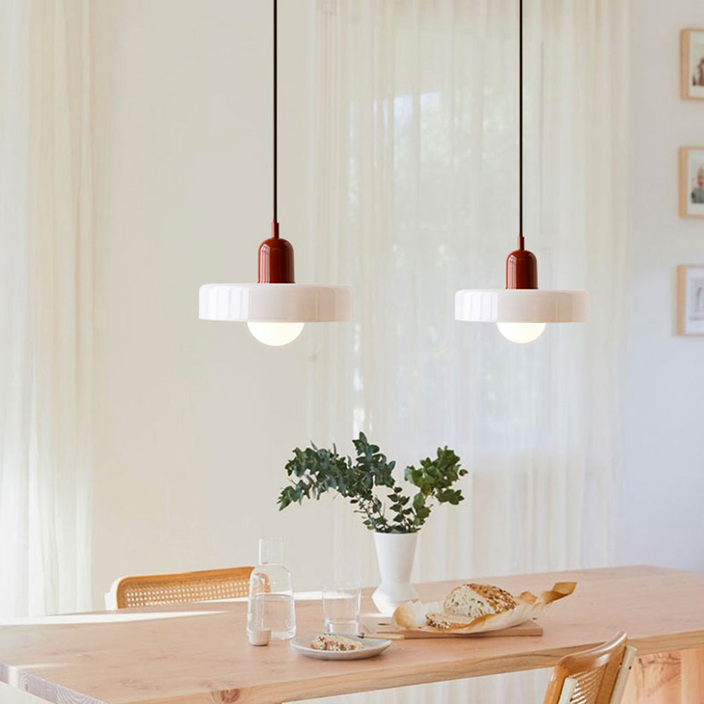Two white glass pendants with dark red caps hanging over a light wood dining table 34