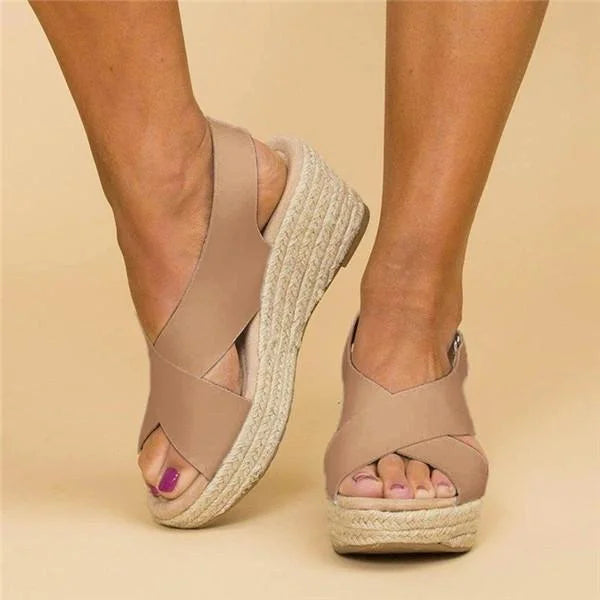 Front three-quarter view of tan crisscross wedge sandals with peep toe and woven jute sole, worn on feet 3