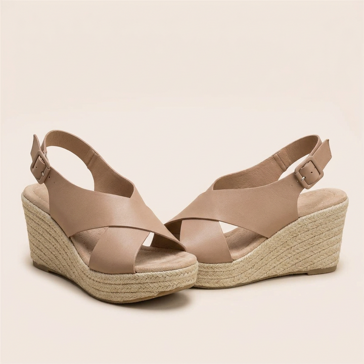 Pair of tan faux leather crisscross wedge sandals with buckled heel straps and braided jute platforms 13