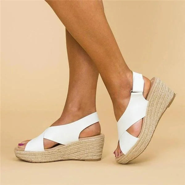 Side view of white crisscross wedge sandals with woven jute soles and adjustable heel straps, worn 5