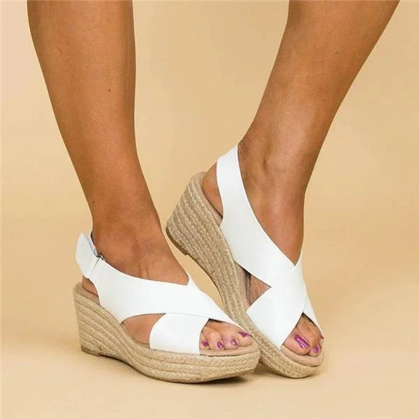 White crisscross wedge sandals on a model's feet, one foot crossed over the other to show the strap 6