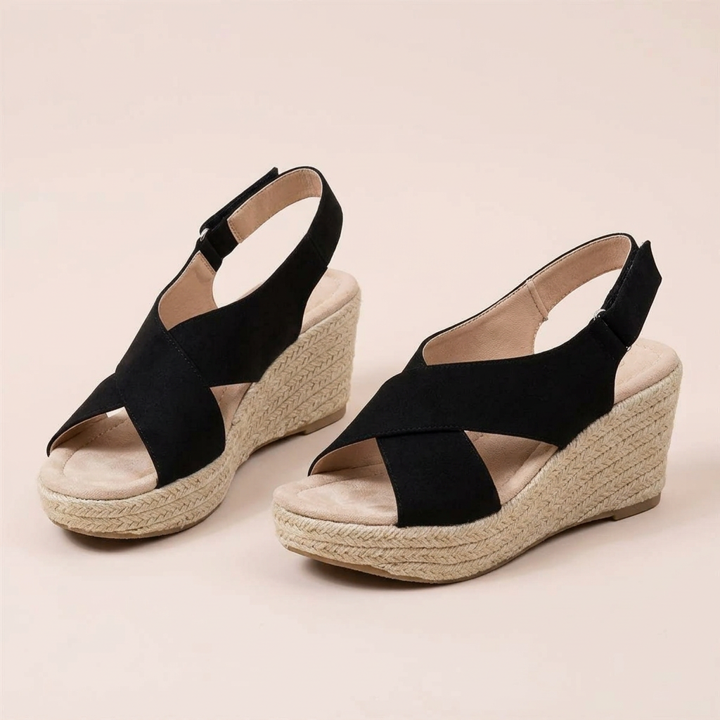 Pair of black crisscross wedge sandals with cushioned footbeds and heel straps on a pale pink background 12