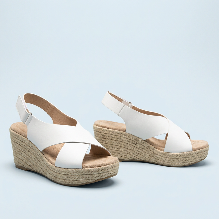 Pair of white crisscross wedge sandals with braided jute platforms and padded footbeds on a light blue background 14