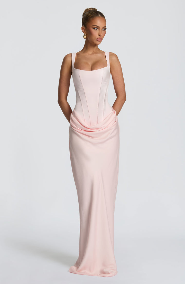 Indy Bodycon Maxi Dress in light pink with draped hips and a long skirt, front view.