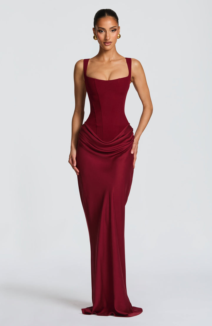 Front view of the burgundy maxi dress on a model, showing the square neckline, corset bodice and draped hip detail. 22