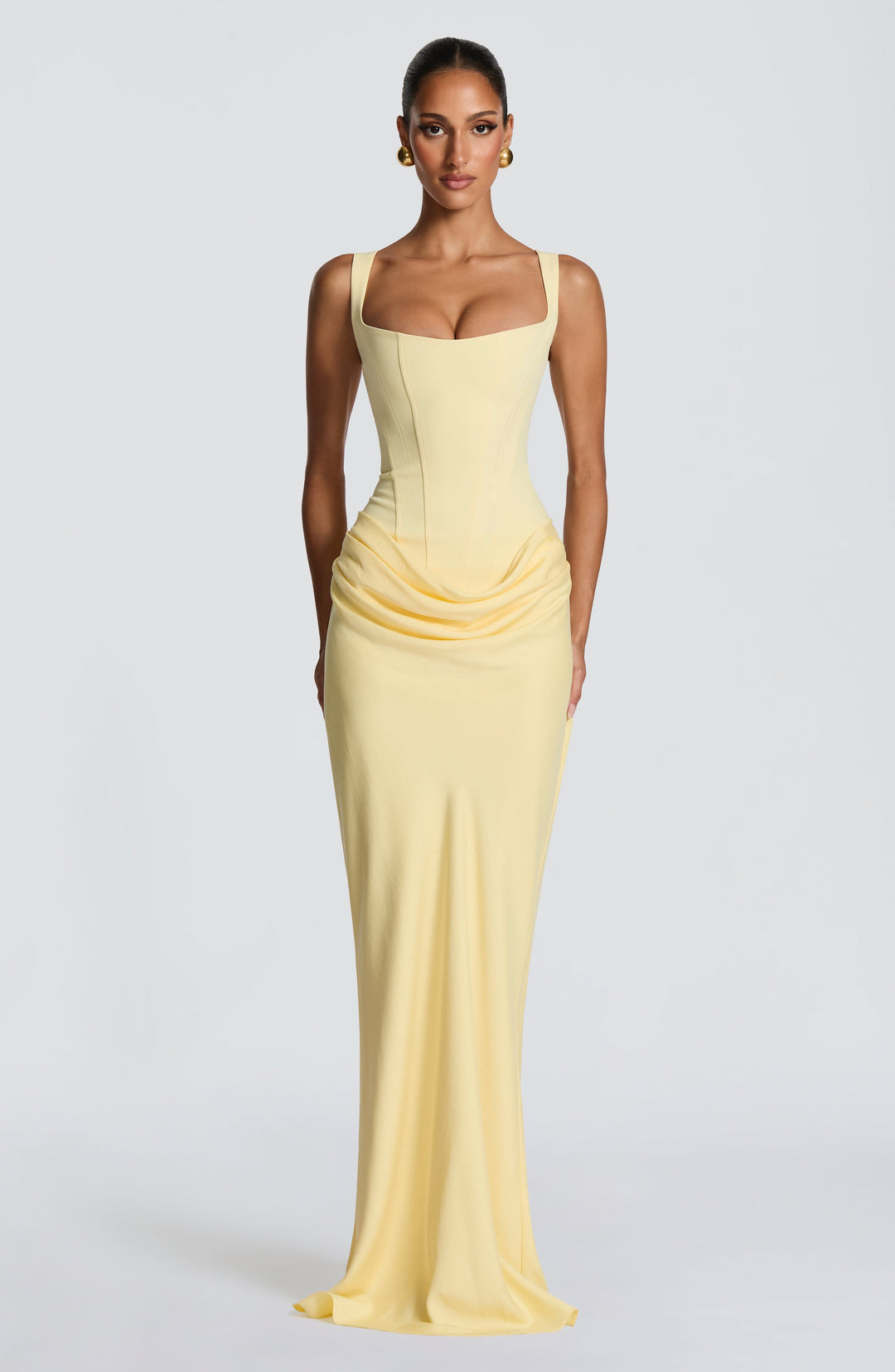 Front view of the pale yellow maxi dress on a model, with square neckline, corset bodice and draped hip detail. 31