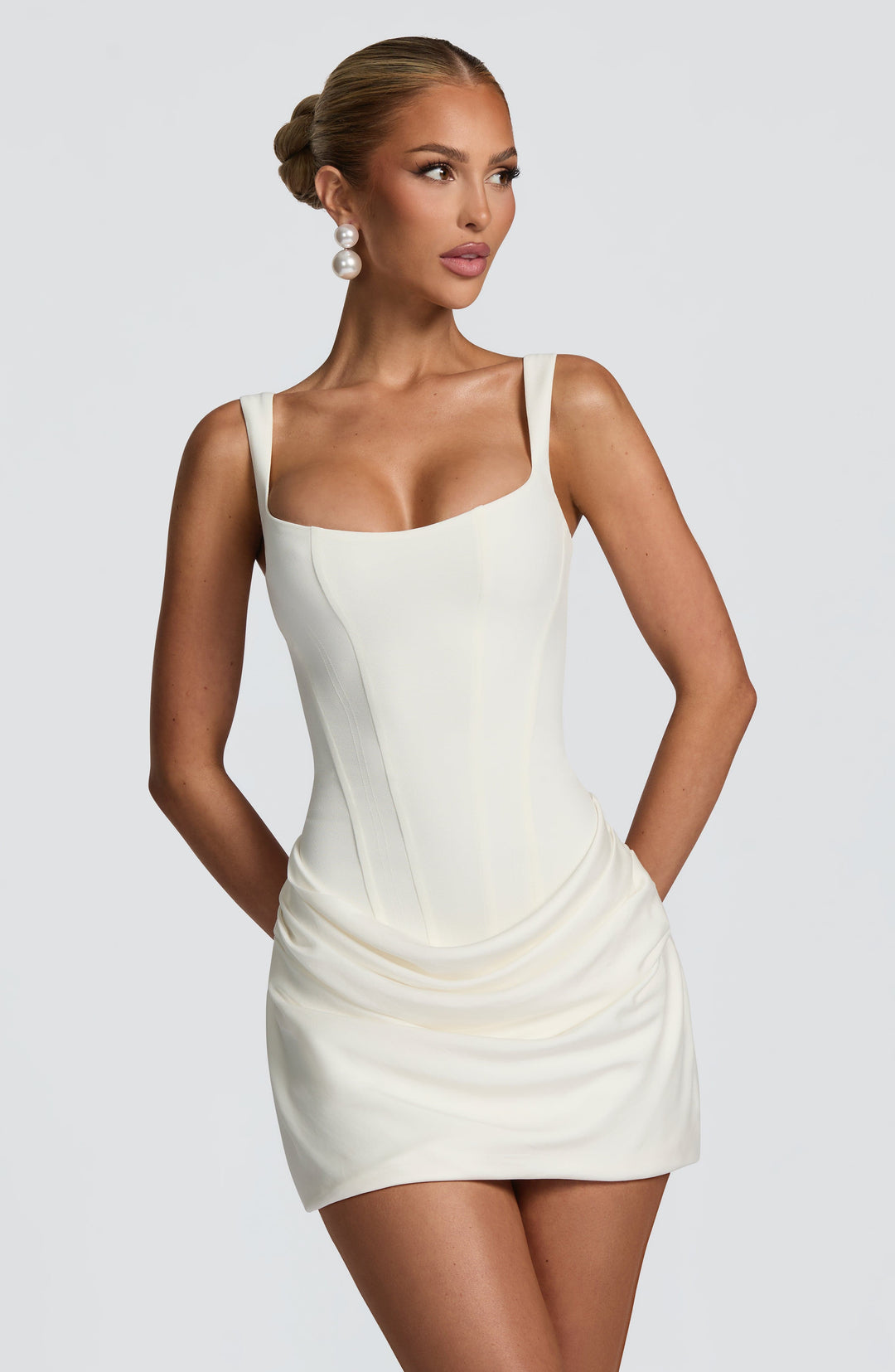 Indy Bodycon Mini Dress in cream white, close front view with corset bodice and draped skirt.