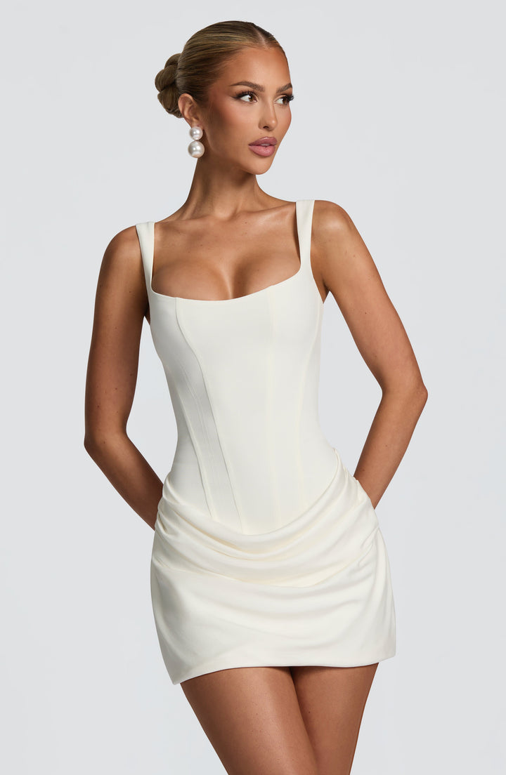 Indy Bodycon Mini Dress in cream white, close front view with corset bodice and draped skirt.