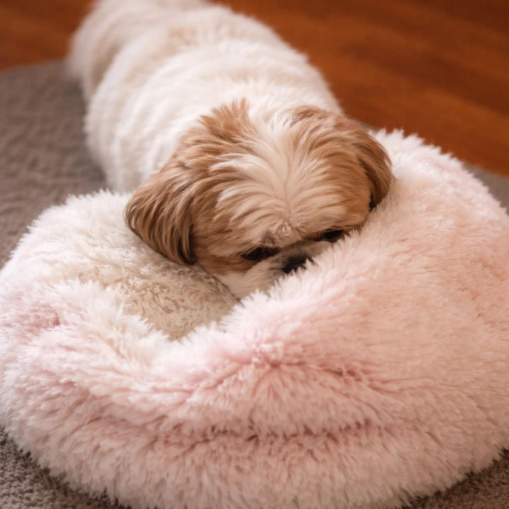 Soft pink plush donut bed with a cream center