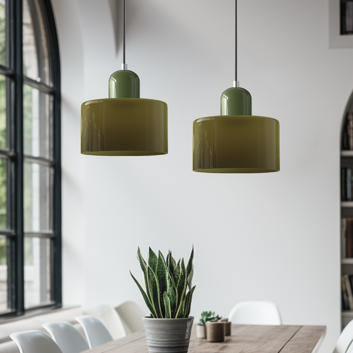 Pair of olive green glossy pendant lights with green caps hanging above a wooden dining table near a tall arched window. 3