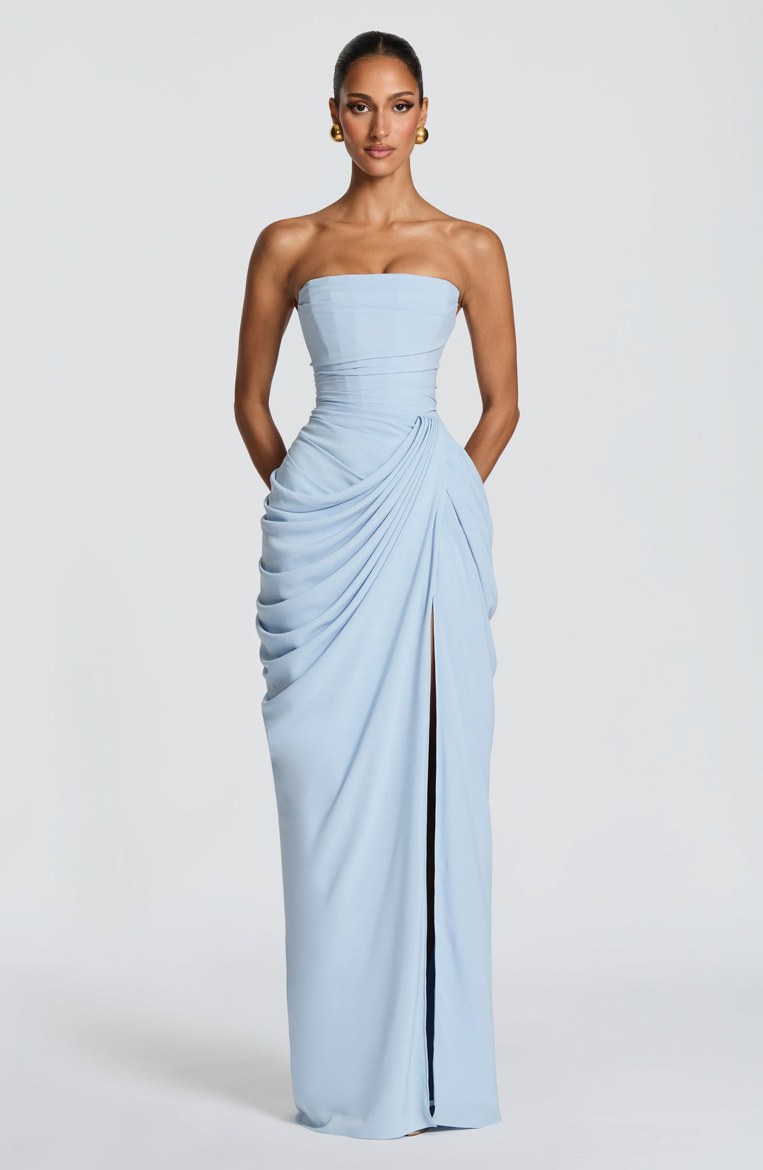 Front view of the light blue strapless dress with hands tucked in side pockets and the slit closed at rest. 23