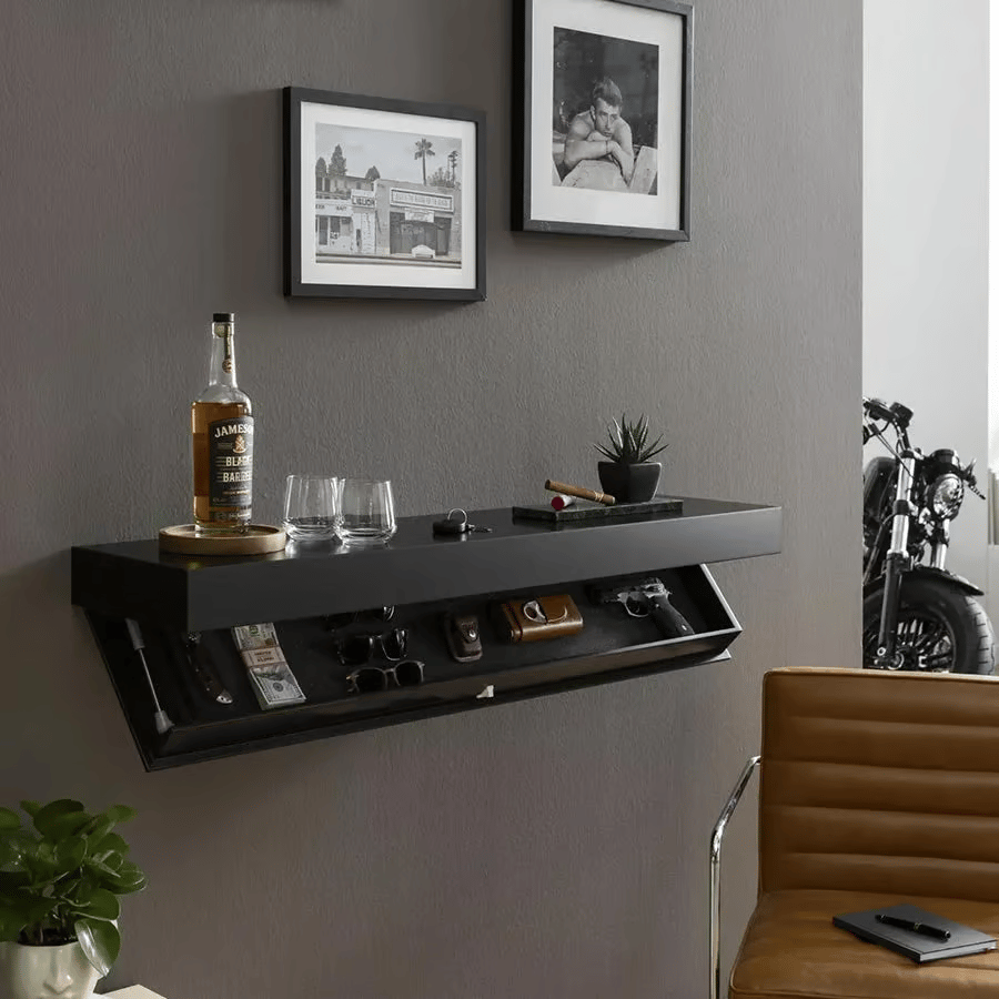 Wall-mounted black shelf styled in a living room with framed photos and a motorcycle, its lower compartment open to show stored valuables. 5