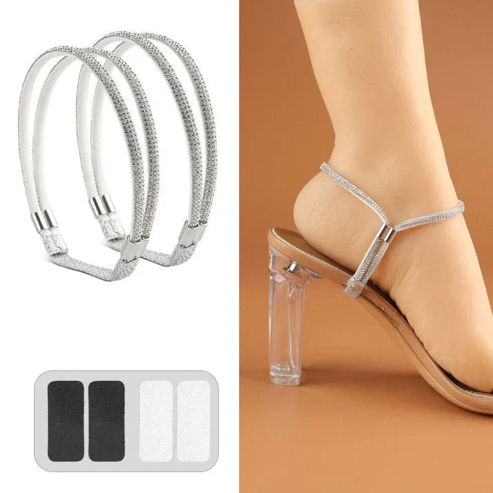 Pair of silver rhinestone elastic shoe straps with adhesive pads beside a foot in a clear-heeled sandal.