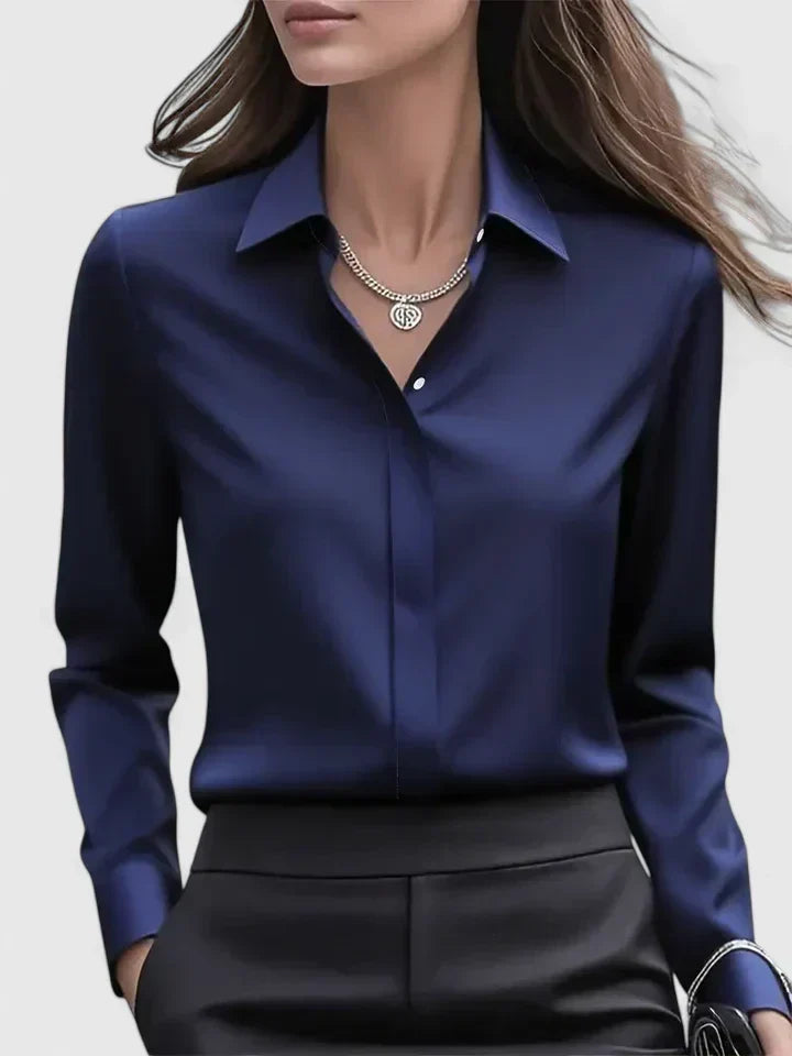 Front view of the navy satin blouse worn by a model with black trousers and a silver chain necklace.