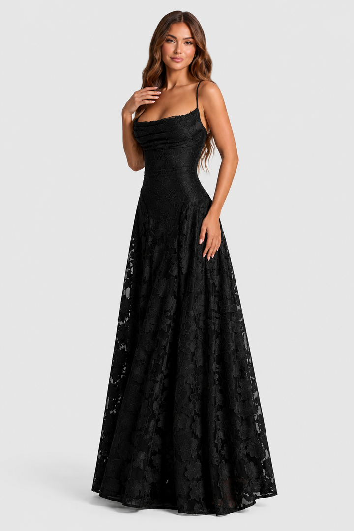 Black floral lace A-line dress with one hand at the collarbone, shown at a slight angle.