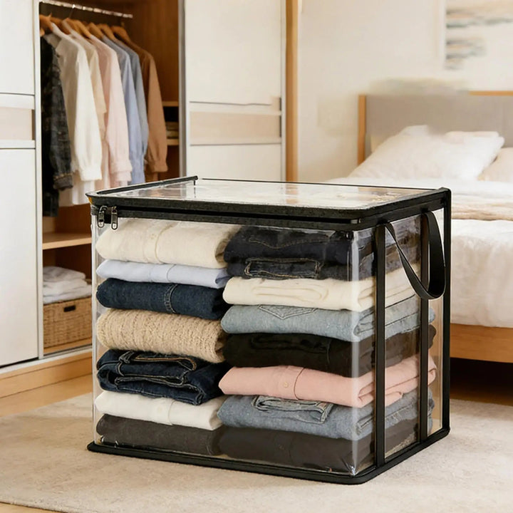 Clear storage bag with black trim and handles, filled with folded sweaters and jeans.