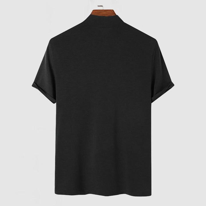 Back view of the black mock-neck tee on a wooden hanger, showing the plain back and rolled sleeve cuffs.