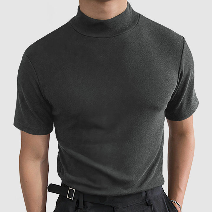 Model wearing the dark gray short-sleeve mock-neck tee, front view, with black trousers and a belted waist.
