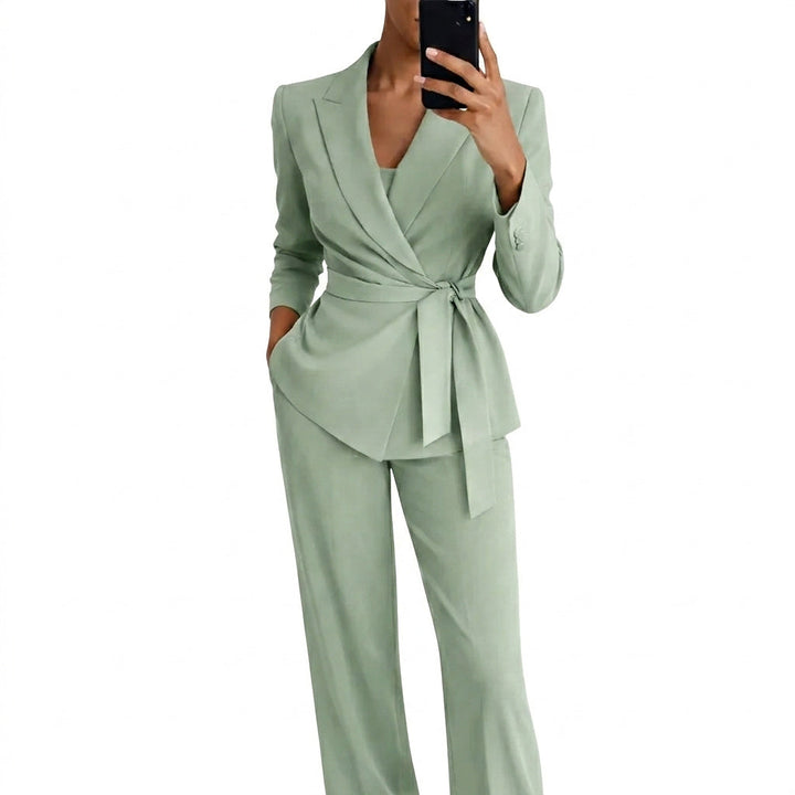 Women's matching blazer and pants set in sage green, shown in a mirror selfie with a wrap front and tie belt.