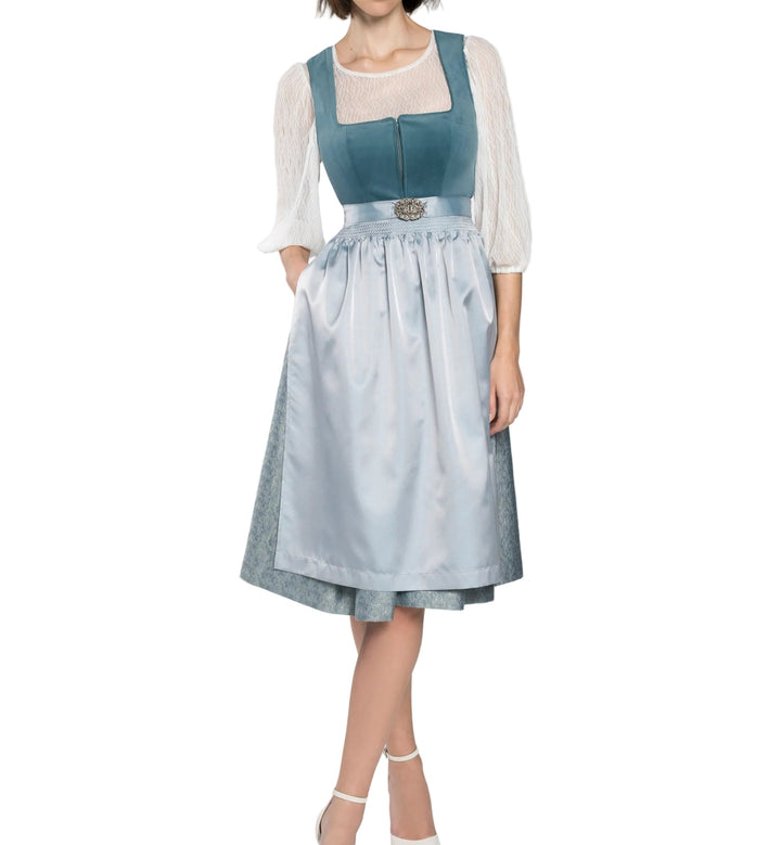 Full-length front view of a model in a blue velvet-look dirndl with a satin apron, silver clasp and sheer lace blouse. 1