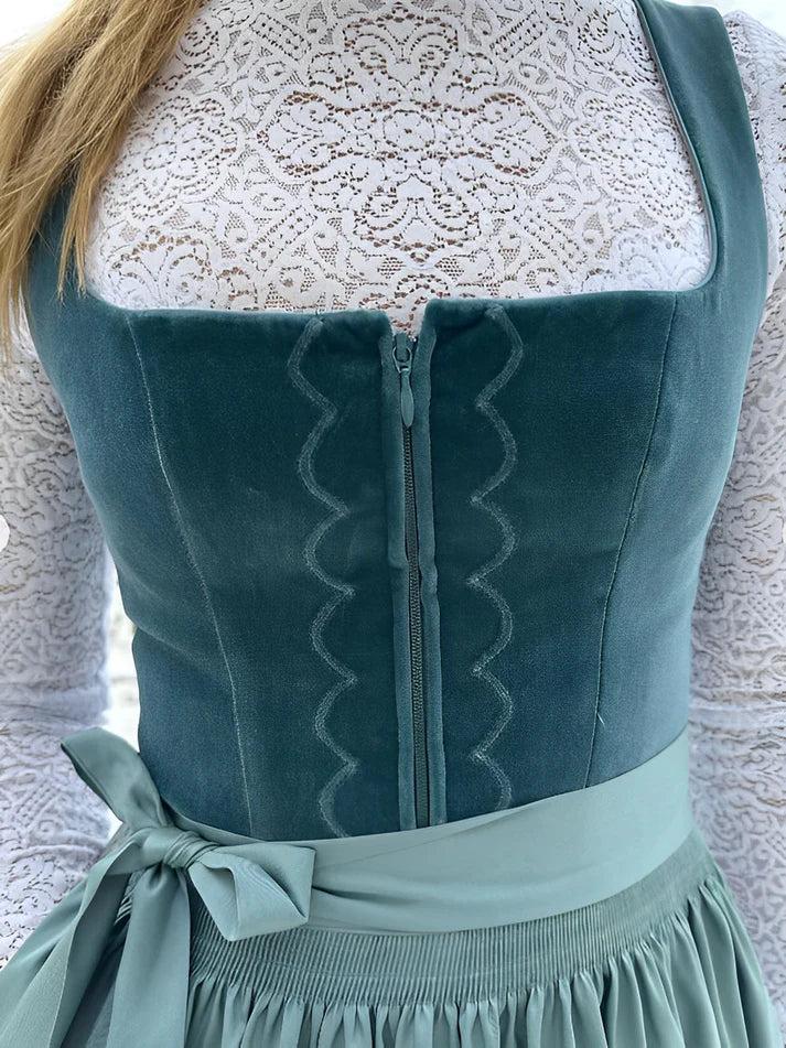 Women's traditional midi dirndl dress detail of the teal velvet bodice with embroidery and apron bow.