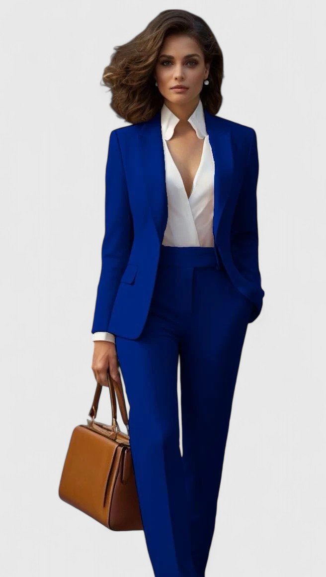 Model wearing the suit in royal blue with a white blouse, holding a tan leather handbag 6