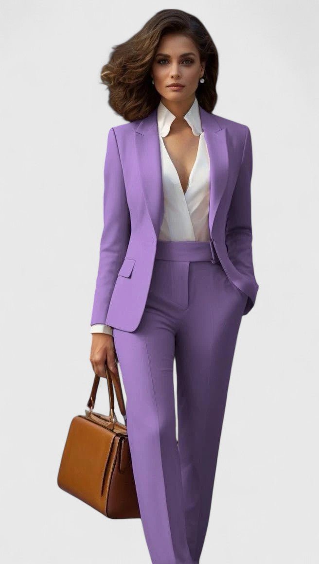 Model wearing the suit in lavender purple with a white blouse, holding a tan leather handbag 9