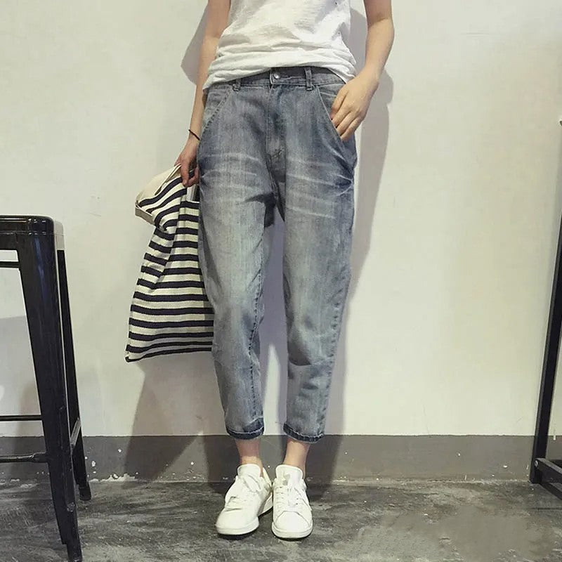 Frau in blauer Jeans und weißen Sneakers, hält gestreifte Tasche, lässiger Look.