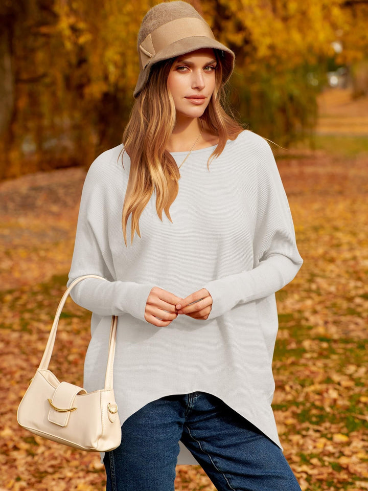 Frau im weißen Pullover und Hut, Herbstlandschaft, beige Handtasche, lässige Mode.