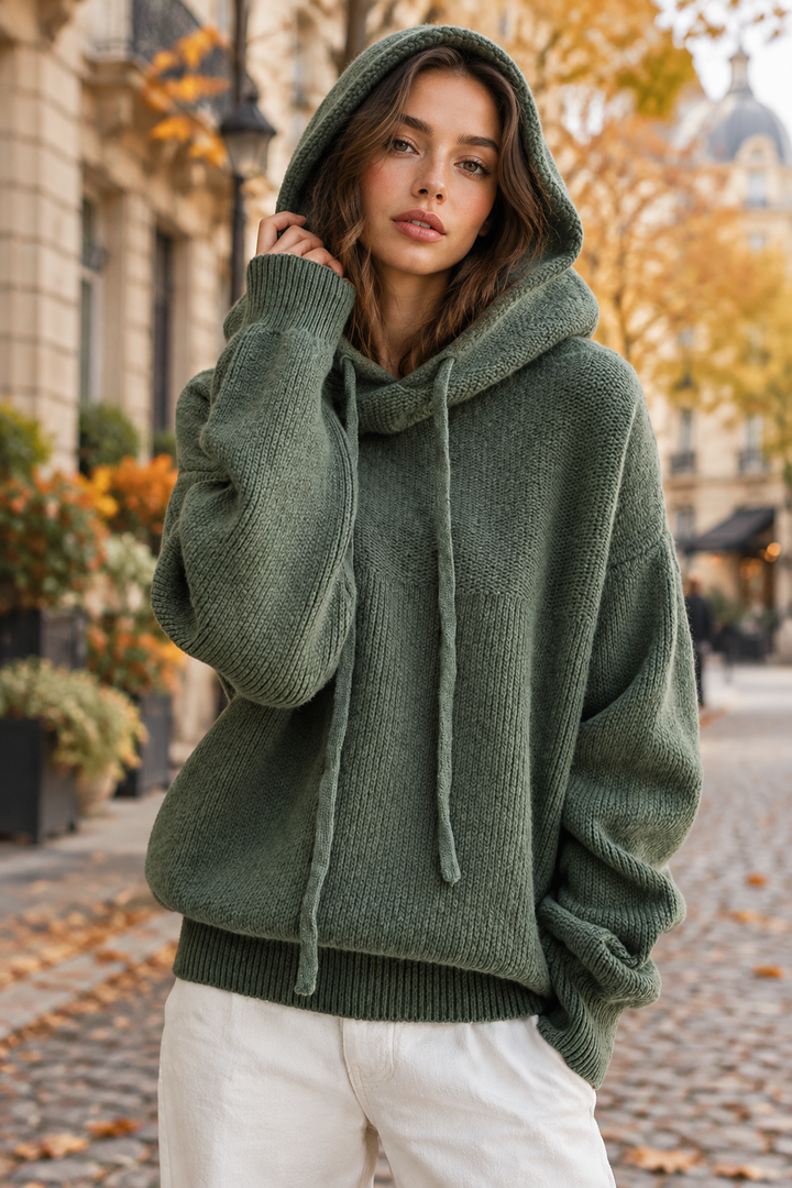 Model in a green knit sweater with the hood up, posing on an autumn Paris street 1