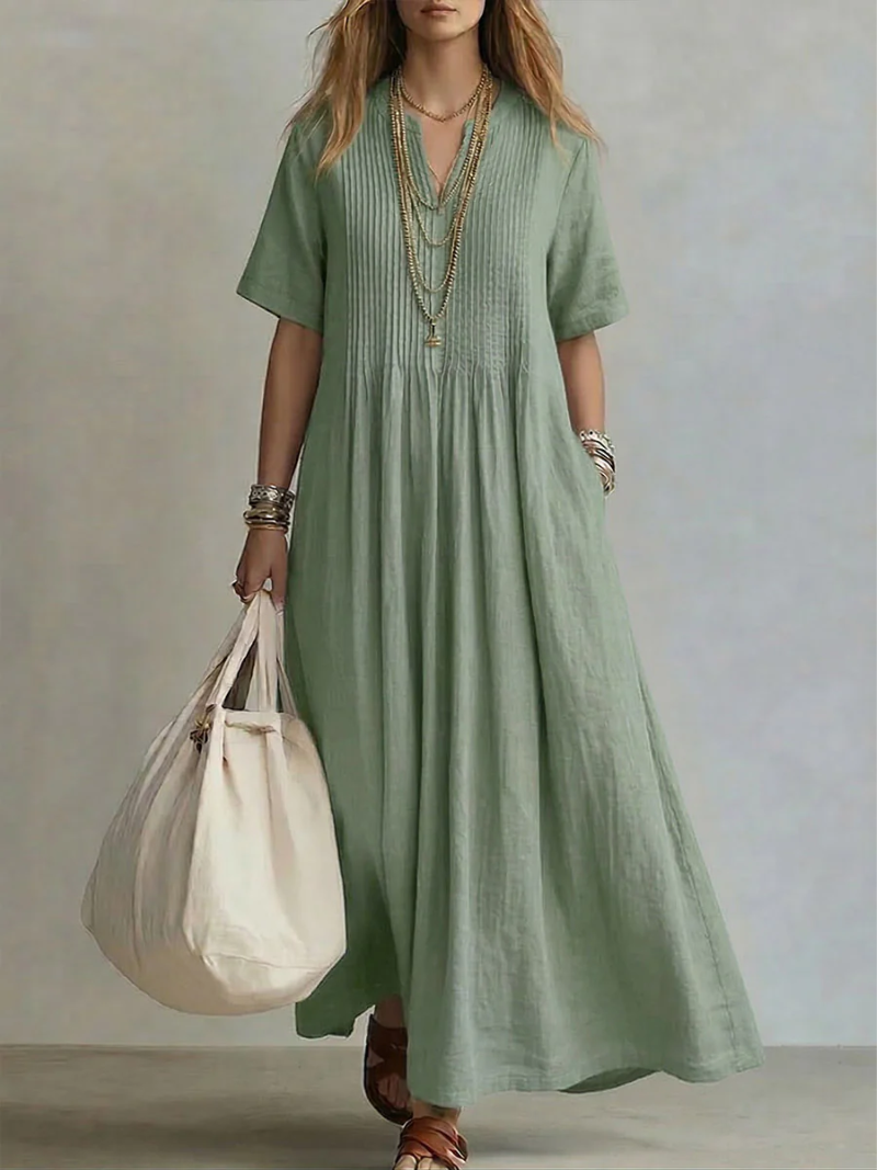 Model wears the short-sleeve pleated dress in soft sage green, detail.