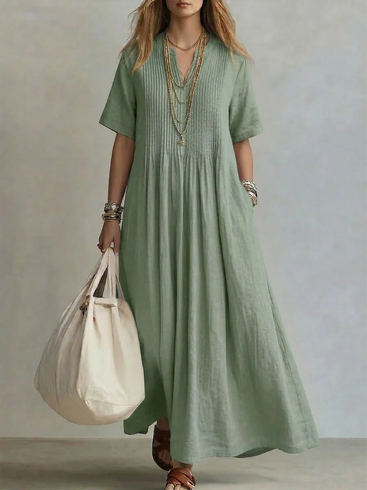 Model wears the short-sleeve pleated dress in soft sage green, detail.