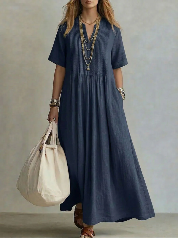 Model wears the short-sleeve pleated dress in deep navy blue, another view.