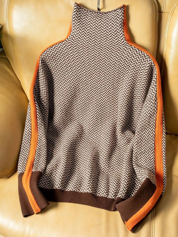 Flat lay of the brown and cream herringbone high-neck sweater with orange side stripes and brown ribbed hem and cuffs, on a tan leather chair. 5