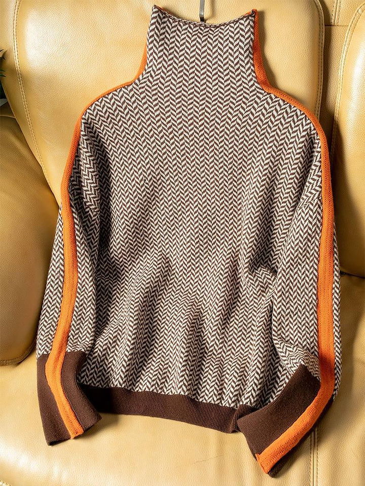 Flat lay of the brown and cream herringbone high-neck sweater with orange side stripes and brown ribbed hem and cuffs, on a tan leather chair. 5
