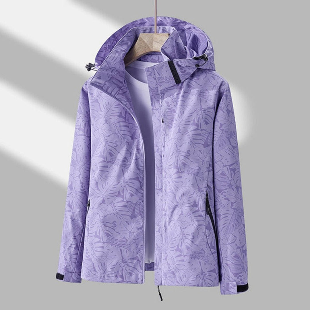 Second view of the lavender leaf-print jacket on a wooden hanger, unzipped, showing the drawcord hood and zippered side pockets. 2