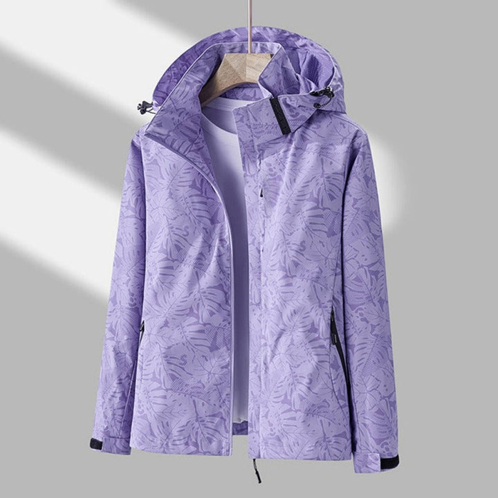 Second view of the lavender leaf-print jacket on a wooden hanger, unzipped, showing the drawcord hood and zippered side pockets. 2