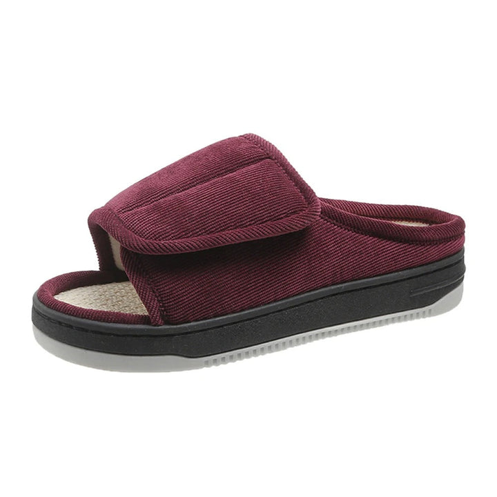 Single burgundy corduroy open-toe slipper with padded adjustable strap, black midsole and gray sole on a white background. 7