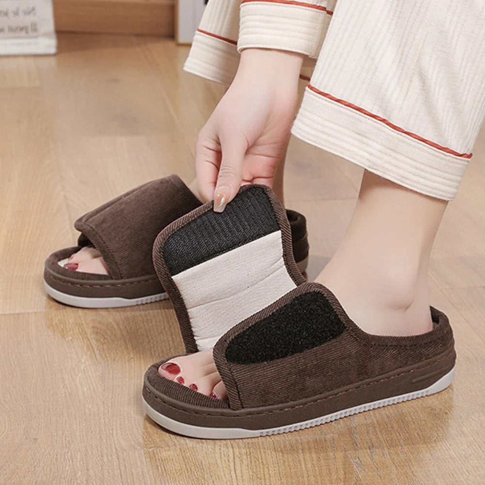 Brown slipper with the strap lifted to show the hook-and-loop fastening and open toe.