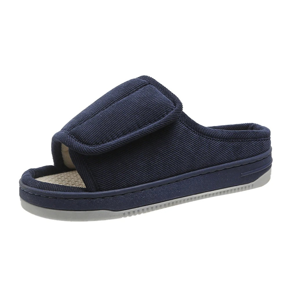Single navy blue corduroy open-toe slipper with padded adjustable strap and light gray sole on a white background. 5
