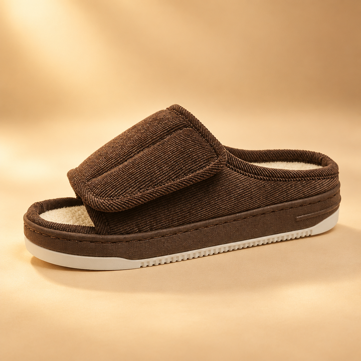 Brown corduroy open-toe slipper with adjustable strap and cream sole, photographed against a soft warm beige backdrop. 11