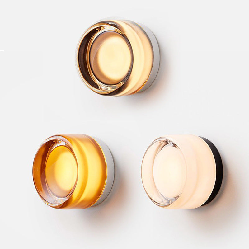 Three sconces arranged on a white wall: a lit smoky amber one on top, then amber and milky white versions below. 5