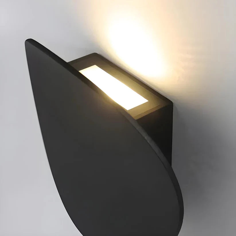 Close-up from above showing the lamp's rectangular light opening between the black disk and the wall mount. 10